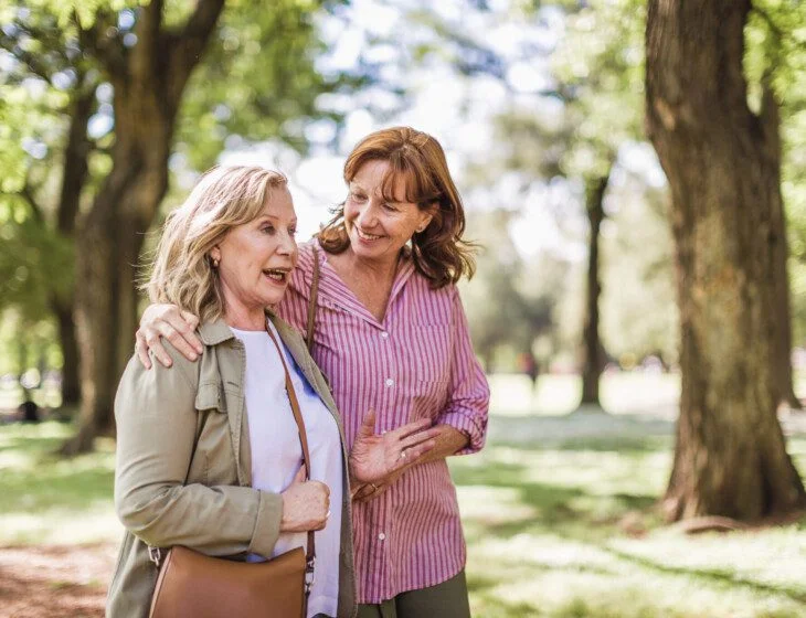 Senior woman and her adult daughter discuss long-term care while on a scenic walk at Oak Trace