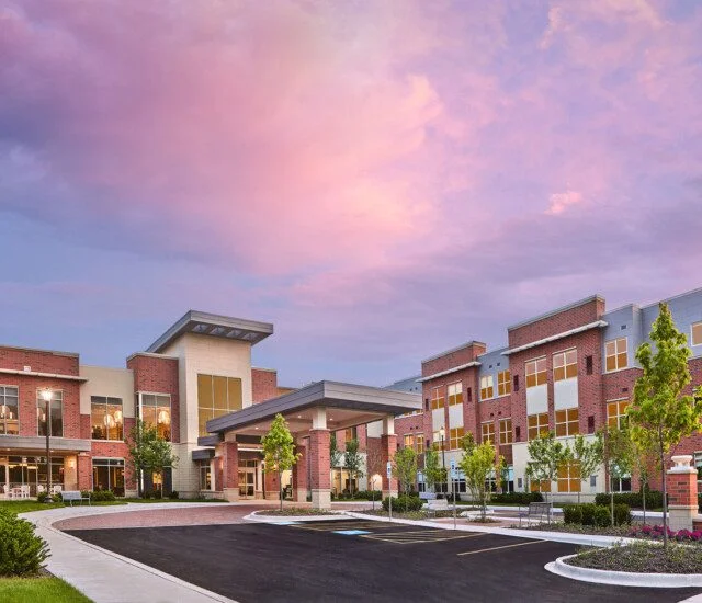 Oak Trace Senior Living Community's entrance and parking lot at sunset