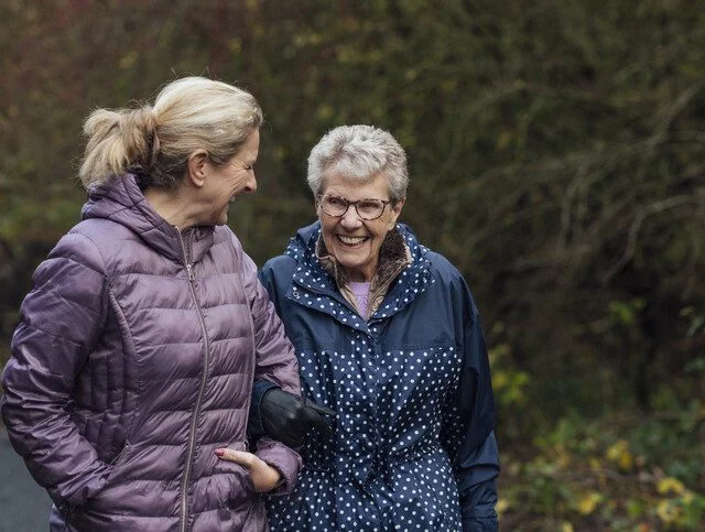 Senior mother happily taking an outdoor stroll with her adult daughter.