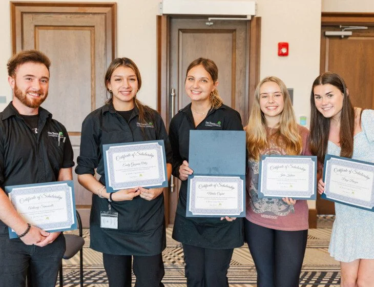 Five people holding certificates and smiling at a ceremony.