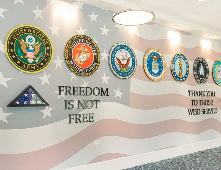 Military branch emblems on a wall with Freedom is not free and Thank you to those who served.