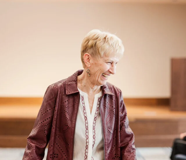 Resident walking the runway in a maroon jacket and cream pants at the Oak Trace fashion show in Downers Grove, IL