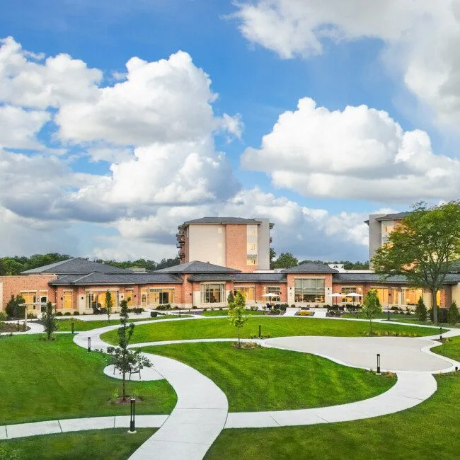 default Courtyard with green lawns, pathways, and surrounding buildings under a partly cloudy sky.