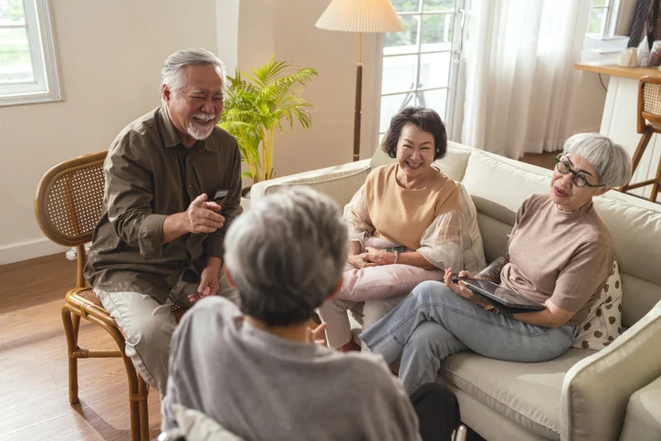 Elderly friends enjoying conversation and laughter in a cozy living room.