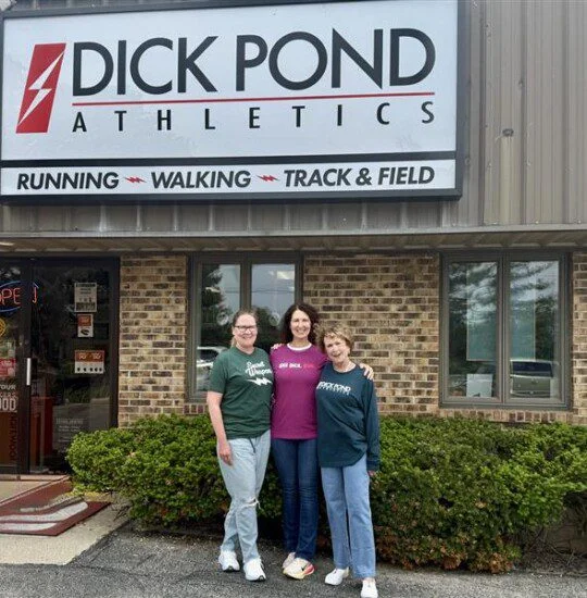 Three people stand outside Dick Pond Athletics store.