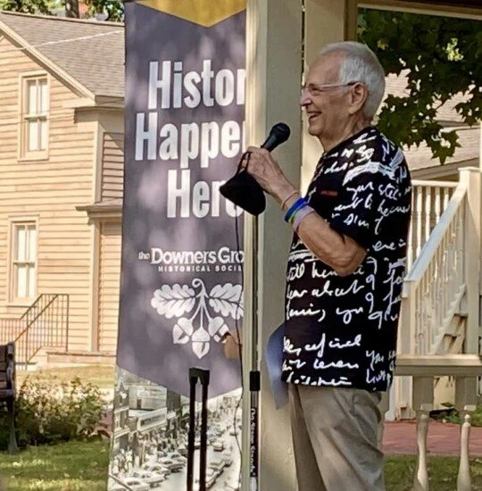 Man speaking into a microphone outside near a banner that reads History Happens Here.