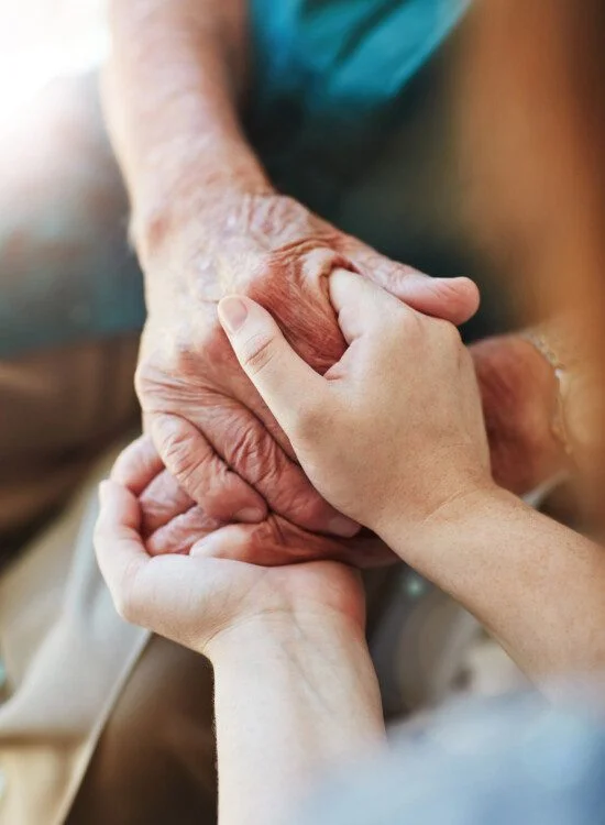 Hands holding an elderly hand gently, conveying care and support.