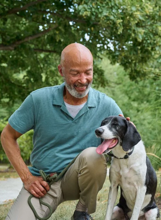 Man kneeling down petting a dog