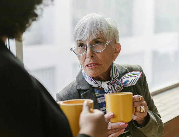 Mature woman drinking coffee talking to another woman