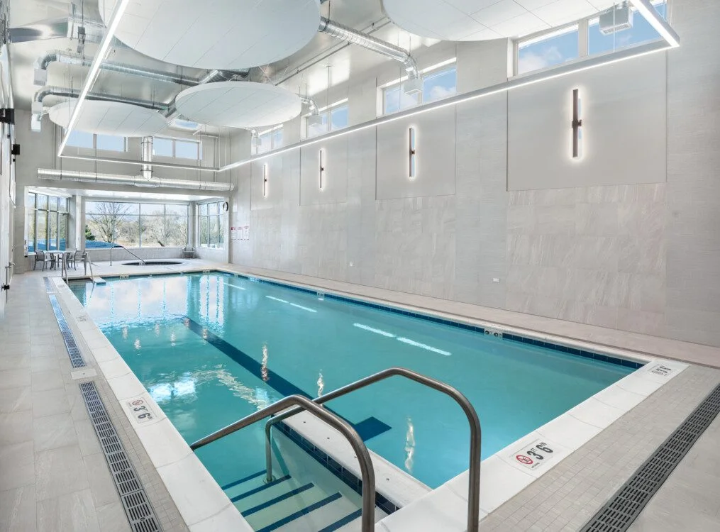 Indoor swimming pool with modern lighting and large windows.