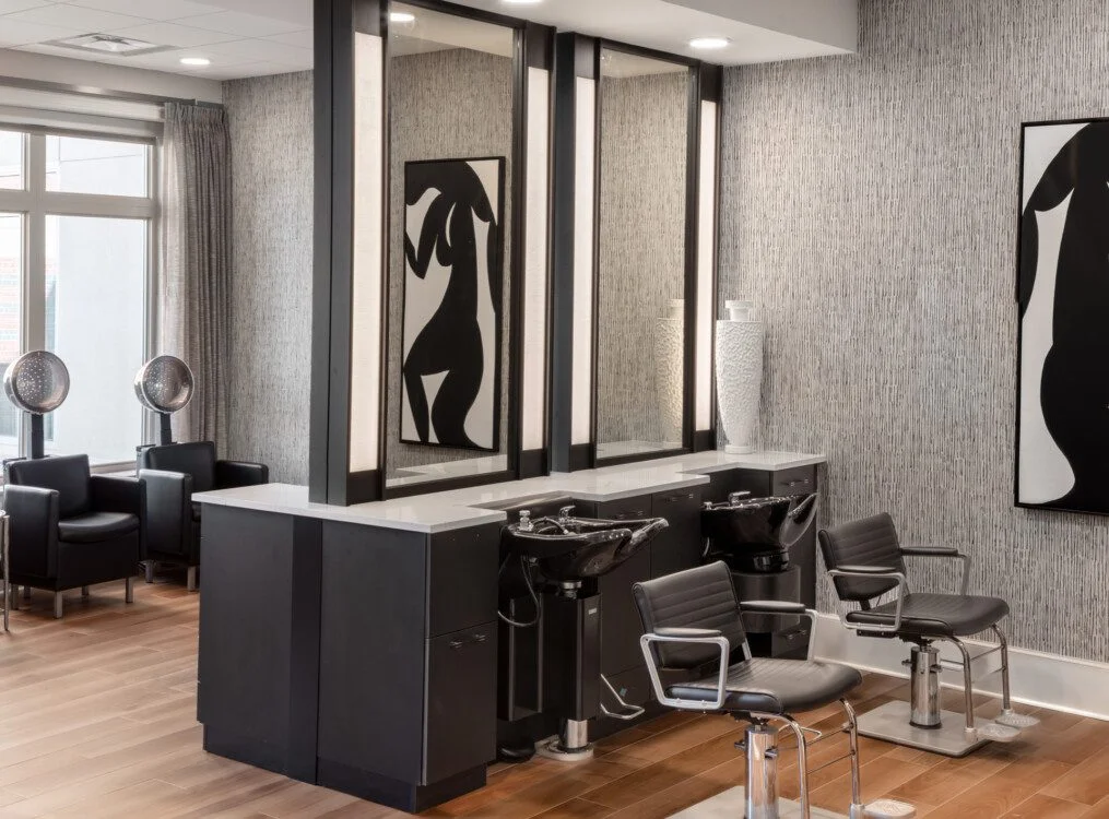 Modern salon interior with styling stations, chairs, and art on textured walls.
