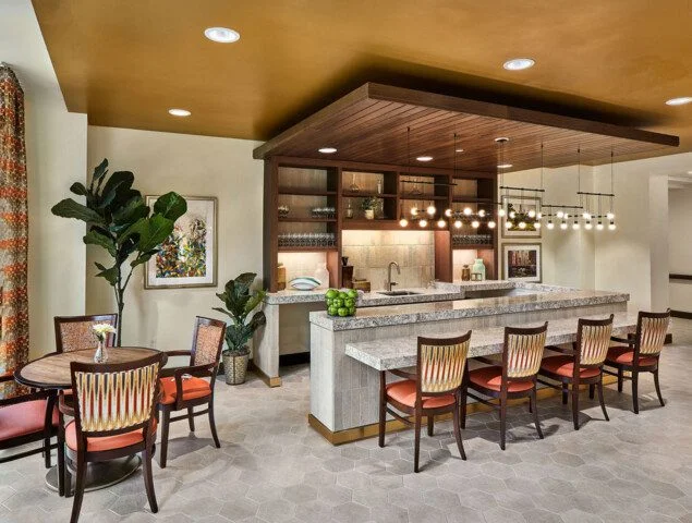 Modern kitchen with bar seating, pendant lights, and a round table with chairs nearby.