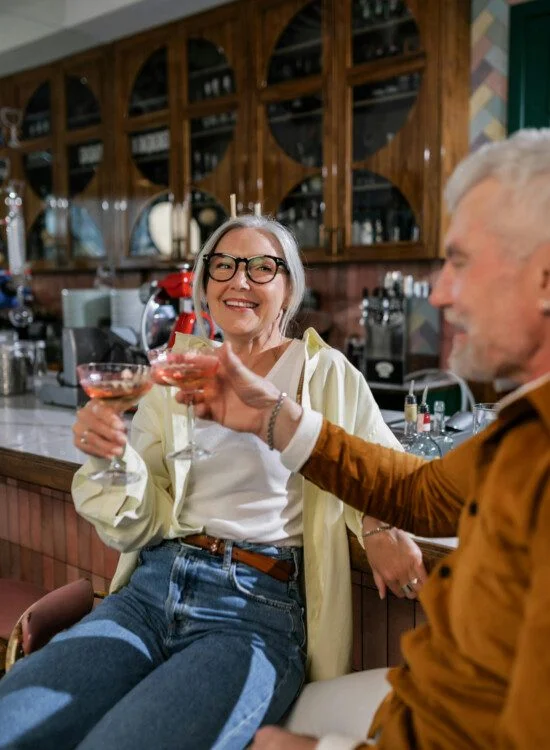 Two people toasting with wine glasses in a cozy bar.