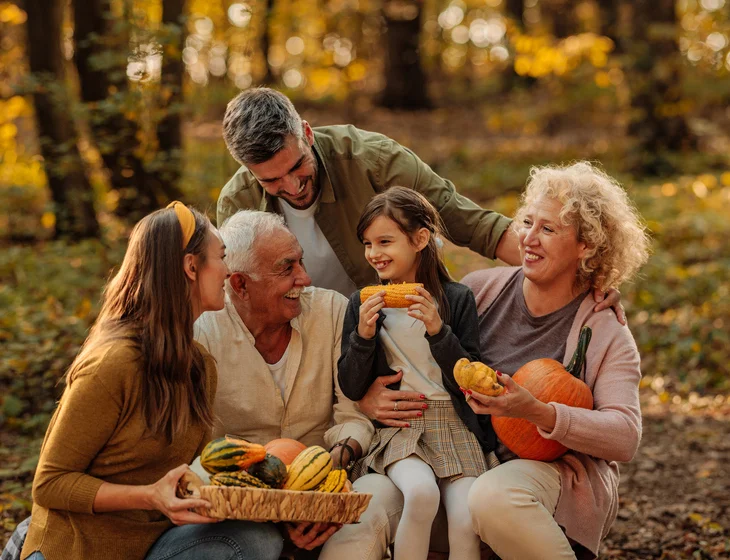Family sitting in the woods holding pumpkins