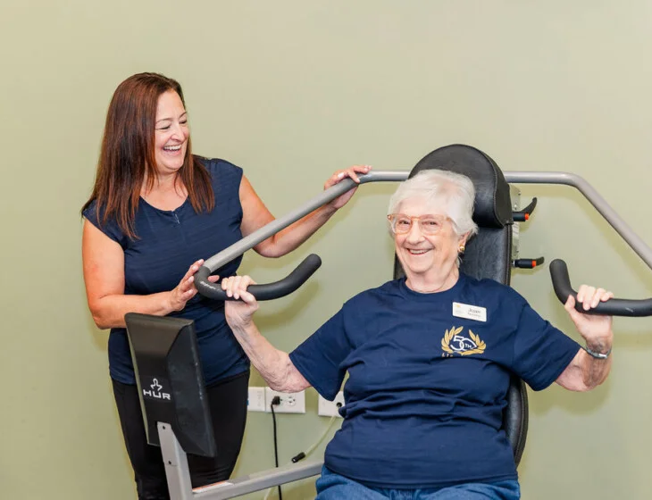 Fitness Supervisor Gina O'Leary helping a resident on strength training equipment at Oak Trace in Downers Grove, Illinois