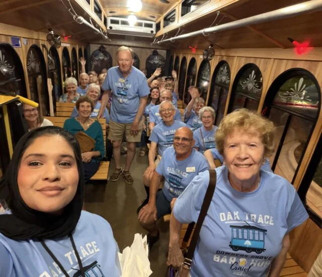 Group on trolley wearing matching blue shirts smiles for photo.
