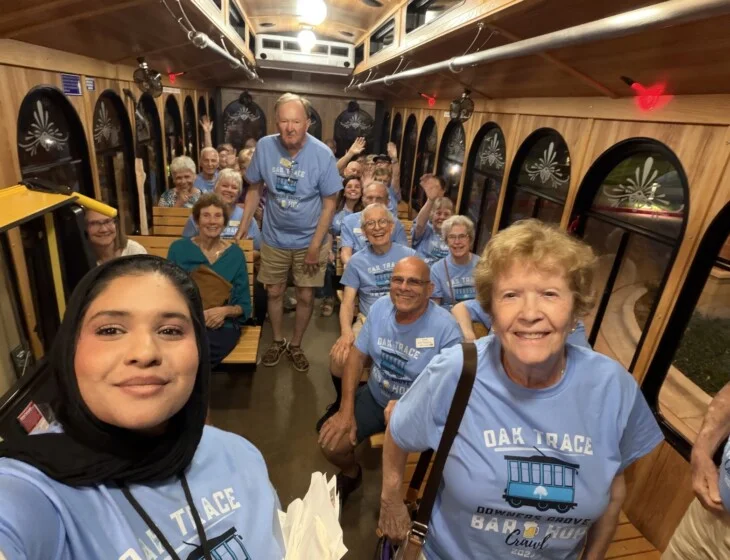 Group on trolley wearing matching blue shirts smiles for photo.