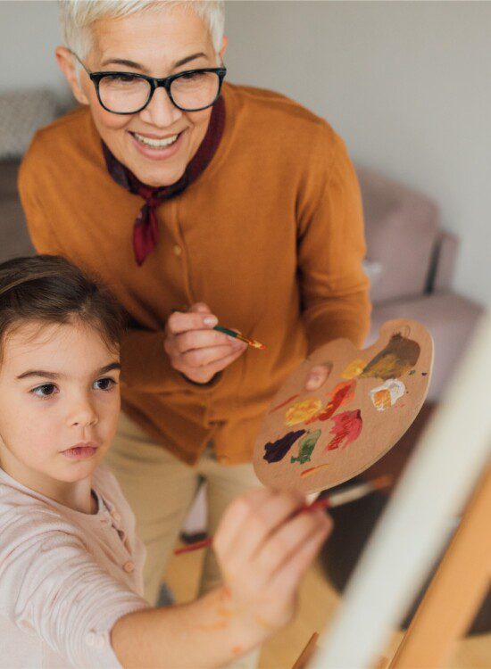 grandmother and granddaughter with paintbrushes and canvas painting
