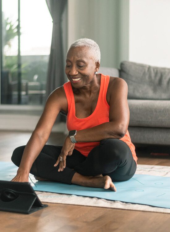 senior woman uses her tablet to do an online yoga course at home