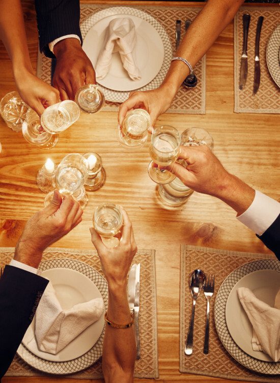 group of elegantly dressed seniors toast wine glasses together at a formal dinner