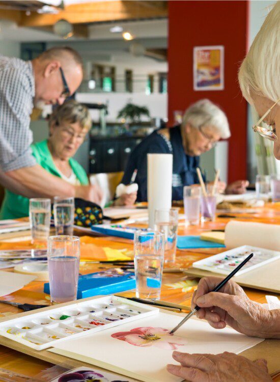 Group of seniors take painting class at their senior living community