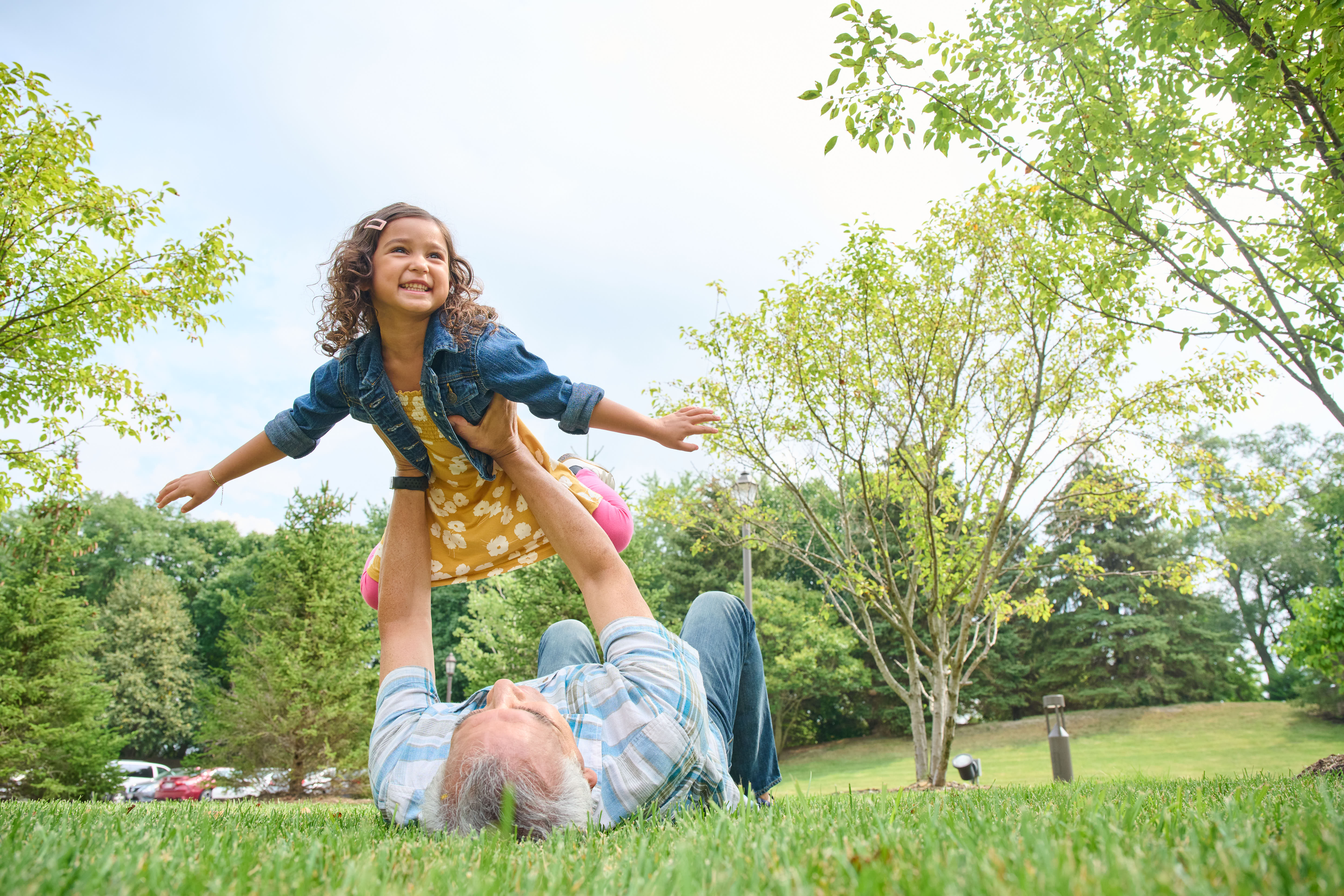 Man laying in grass holding granddaughter