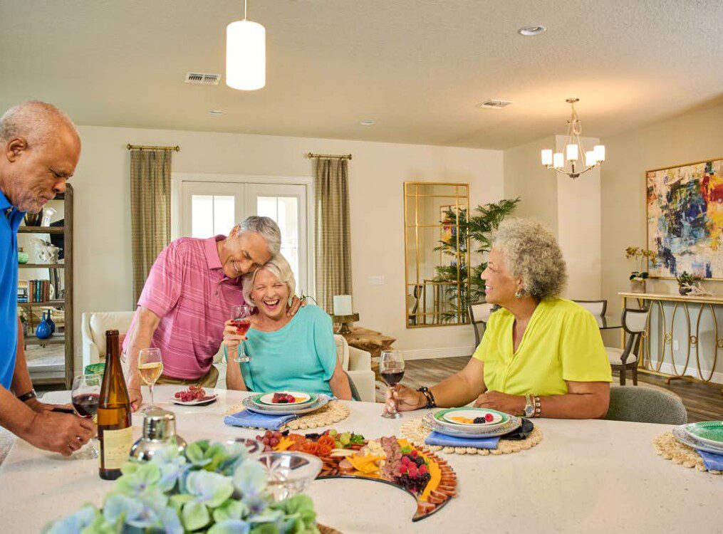 group of seniors gather in a villa home for snacks, drinks, and games