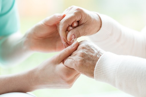 close up of a caregiver and senior holding hands