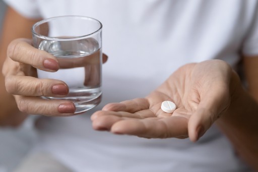 senior taking a medication with a glass of water