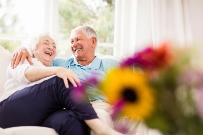 senior couple laughing together on a couch in their senior apartment home