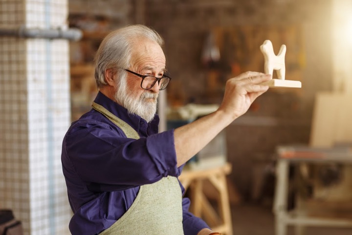 Senior man holding up woodworking project