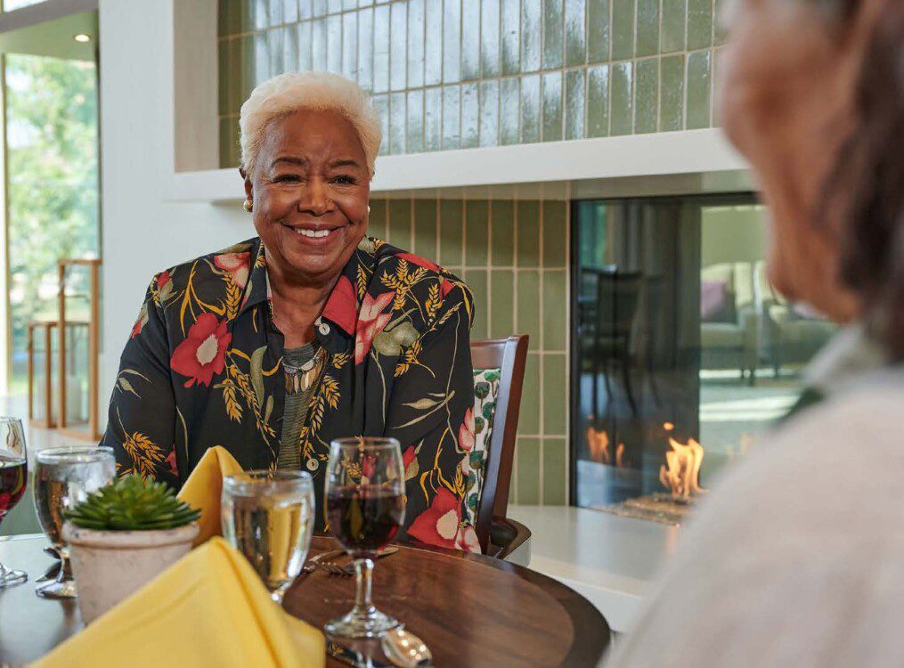 senior woman smiles at her companion while dining indoors at Oak Trace Senior Living Community