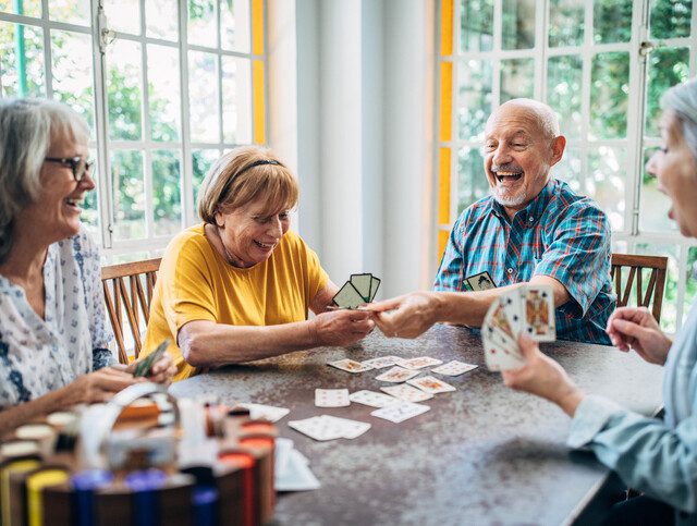 group of seniors laugh and play card games together at Oak Trace Senior Living Community