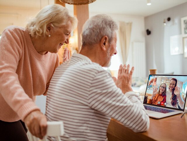 senior couple smiles and video chats with their grandchildren while in their senior living apartment