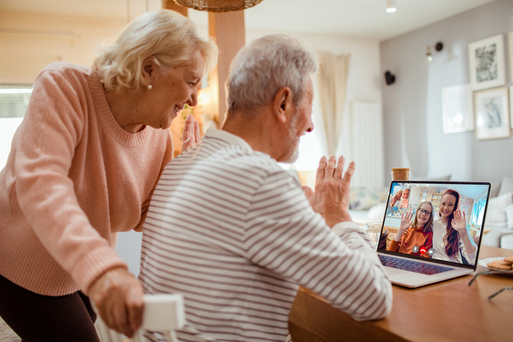 senior couple smiles and video chats with their grandchildren while in their senior living apartment