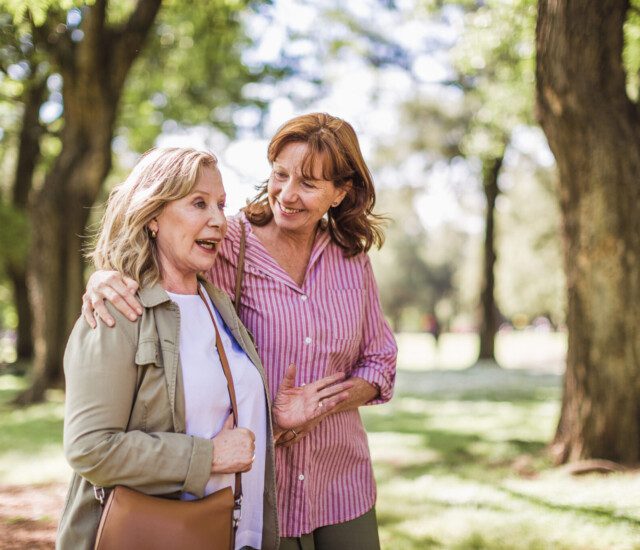 Senior woman and her adult daughter discuss long-term care while on a scenic walk at Oak Trace