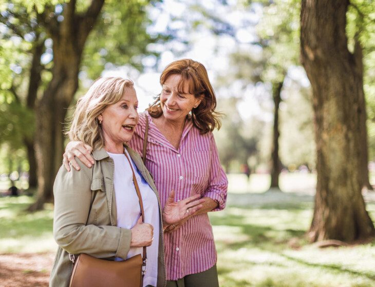 Senior woman and her adult daughter discuss long-term care while on a scenic walk at Oak Trace