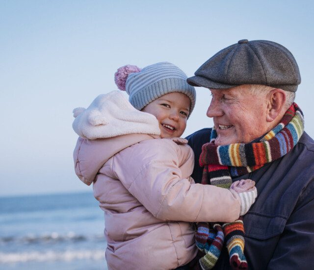 Grandfather and granddaughter bundled up in winter clothing, smiling