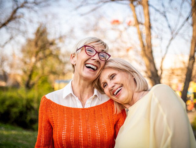 Two older women smiling and embracing.