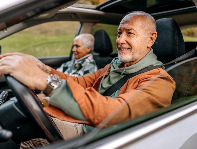 senior man and his wife take a leisurely drive on a sunny day