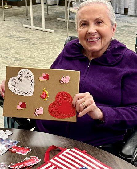 Oak Trace Senior Living resident smiles and holds up her valentine's day card creation