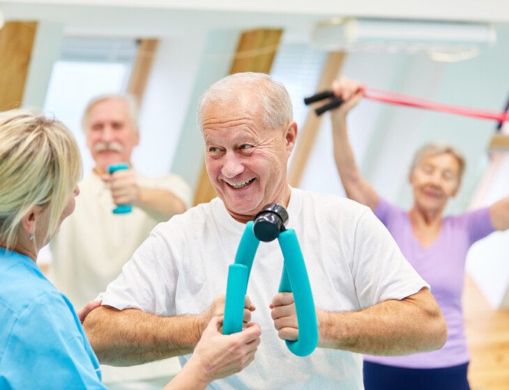 Senior man doing physical therapy exercises in a group class with others