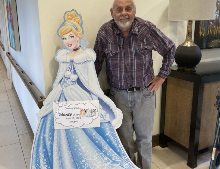 George Hlava, an Oak Trace Senior Living Community resident, smiles while posing next to a cut-out image of Cinderella