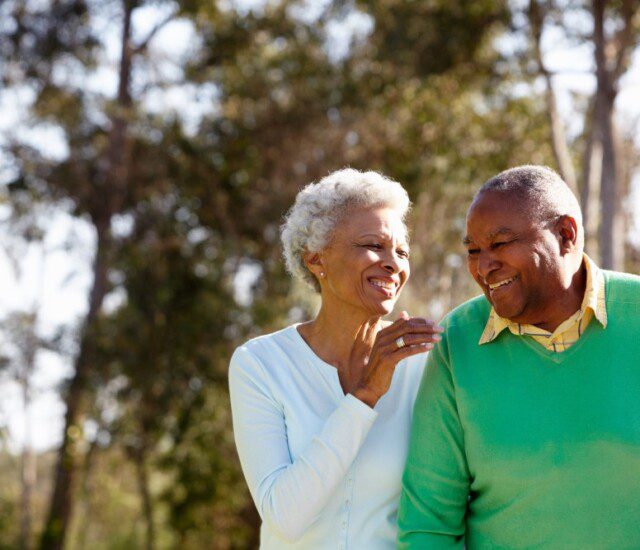 senior couple smiles while on a scenic walk outside of Oak Trace Senior Living Community