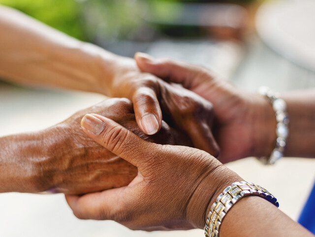 close up of senior and their caregiver clasping hands