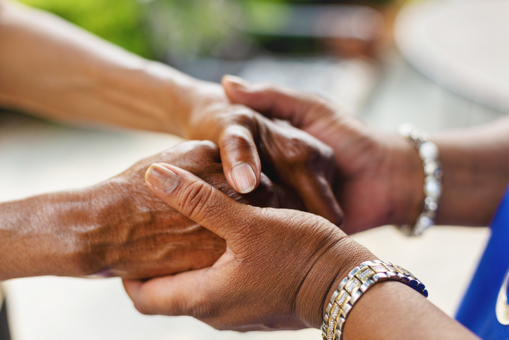 close up of senior and their caregiver clasping hands