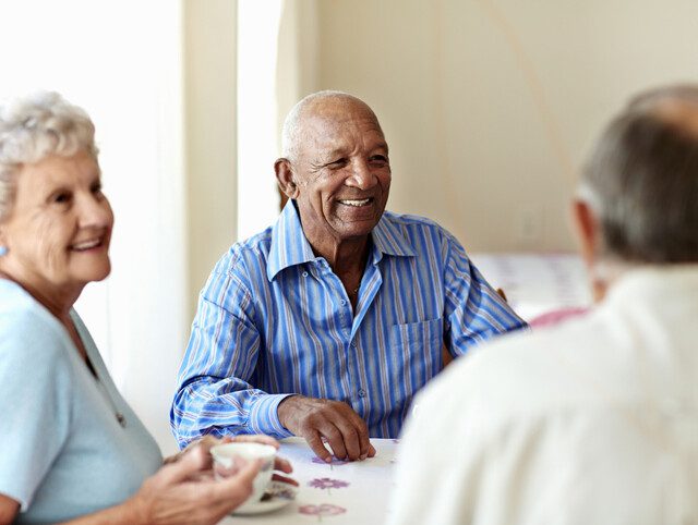 group of senior friends smile and enjoy good conversation over coffee at Oak Trace Senior Living Community