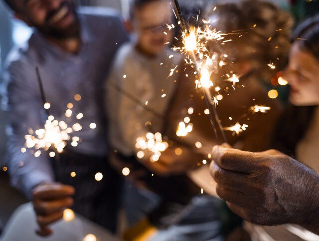 close-up of a family holding lit sparklers and celebrating New Years