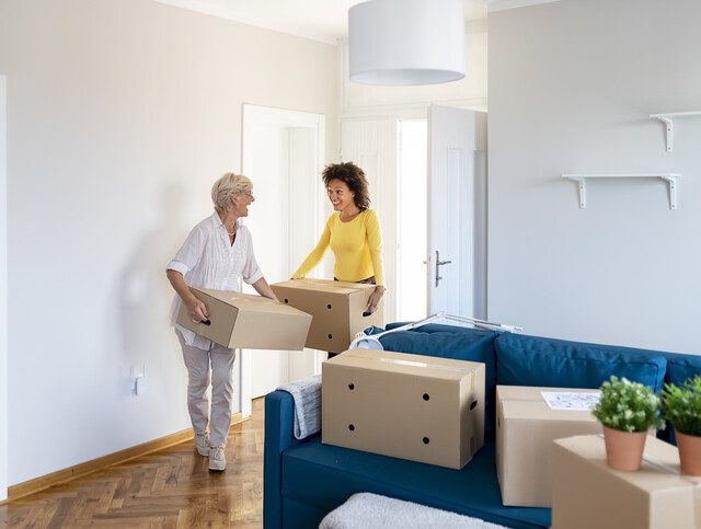 senior woman is helped by her adult daughter while packing to move to a senior community