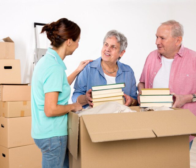 A senior couple receives help unpacking after a move to their senior apartment